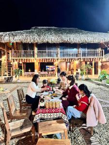a group of people sitting at a table in front of a hut at Framstay Mây Sườn Đông in Ðại Từ