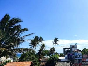 a group of palm trees and a building with a tower at Ahangama Wave Nook in Ahangama