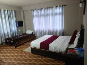 a bedroom with two beds and a window with curtains at Hotel Silver Cloud in Pelling +2 photos