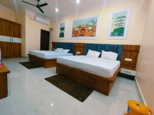 a hotel room with two beds and paintings on the wall at Hotel Orchha Heritage in Orchha