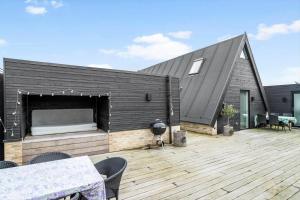 a black house with a deck with a grill at 40160-Juelsminde-Hasselvej-8 in Juelsminde