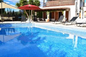 a blue swimming pool with a red umbrella and chairs and an umbrella at Casa Blanca Suiza in Benissa