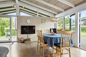 a dining room with a table and chairs and a tv at 30536-Odder-Strandagervej-3 in Odder