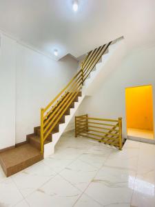 a staircase in a white room with a yellow wall at Mubarak Hostel Syari'ah in Bukittinggi