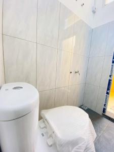 a bathroom with a white toilet and a white tiled wall at Mubarak Hostel Syari'ah in Bukittinggi