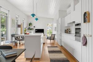 a kitchen with white cabinets and a dining room at 40171-Juelsminde-Poppelalle-29 in Juelsminde