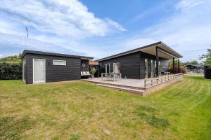 a black house with a deck and a yard at 40171-Juelsminde-Poppelalle-29 in Juelsminde