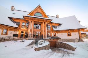 a log home with snow on the ground at Apartament Tatry One in Zakopane