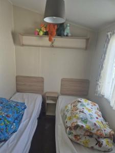 a bedroom with two beds and a window and a shelf at 3 bed Caravan wink ups towyn in Kinmel Bay +7 photos