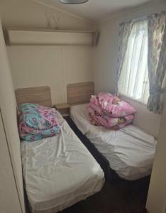 two beds in a small room with pillows on them at 3 bed Caravan wink ups towyn in Kinmel Bay