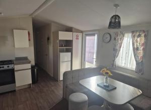 a living room with a couch and a table and a kitchen at 3 bed Caravan wink ups towyn in Kinmel Bay