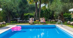 a swimming pool with two women sitting in chairs next to at Aparthotel Ano in Acharavi