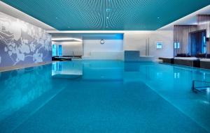 a large swimming pool with blue water in a building at Giardino Mountain in St. Moritz
