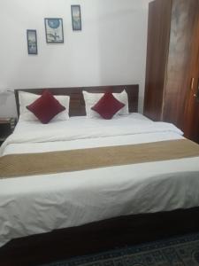 a bedroom with a large bed with two red pillows at Hotel Rajpal in Jaipur