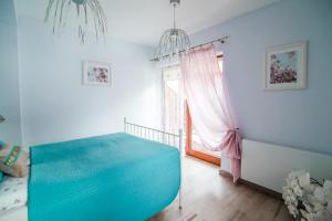 a bedroom with a blue bed and a window at Apartament Tatry One in Zakopane