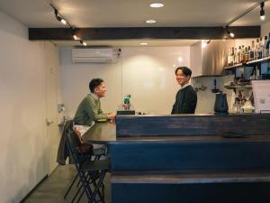 two men sitting at a counter in a bar at En- Hostel & Café bar in Amami