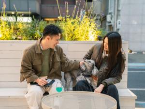 a man and woman sitting on a bench with a dog at En- Hostel & Café bar in Amami