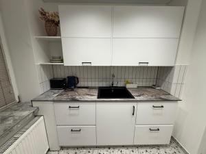 a kitchen with white cabinets and a sink at Cozy Stay Marijampolė in Marijampolė +11 photos