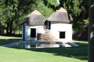 a small white building with a grass roof and a pool at Beaconsfield Farm in Hofmeyr