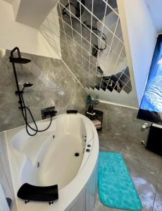 a large white tub in a bathroom with a blue rug at Phöenixpalace Whirlpool & Infarotsauna in Dortmund +6 photos