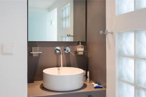 a bathroom with a sink, mirror, and bathtub at Kanale's Rooms & Suites in Naousa