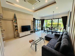 a living room with a couch and a tv at Duangtham luxury Pool Villa in Ban Khlong Haeng