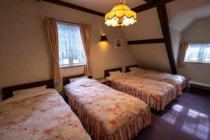 a hotel room with three beds and a chandelier at ray of hakuba 白馬の輝き in Hakuba +20 photos
