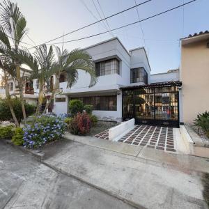 a white building with palm trees in front of it at Casa Lucy Alojamientos in Palmira