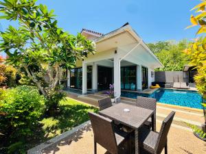 a patio with a table and chairs in front of a house at Duangtham luxury Pool Villa in Ban Khlong Haeng