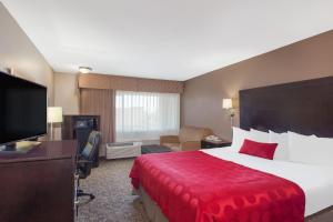 a hotel room with a large bed with a red blanket at Ramada by Wyndham Fresno North in Fresno