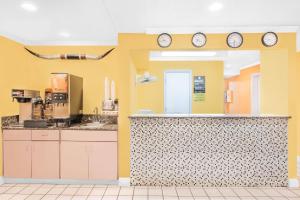a kitchen with yellow walls and clocks on the wall at Super 8 by Wyndham Van Horn in Van Horn