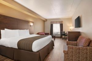 a hotel room with a large bed and a chair at Days Inn by Wyndham Leamington in Leamington +38 photos