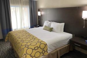 a hotel room with a large bed with a yellow blanket at Baymont by Wyndham Topeka in Topeka
