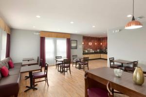 a living room with a couch and tables and chairs at Super 8 by Wyndham Carrizo Springs in Carrizo Springs