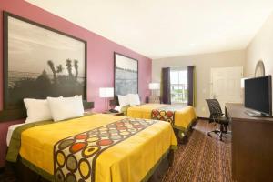 a hotel room with two beds and a desk at Super 8 by Wyndham Carrizo Springs in Carrizo Springs