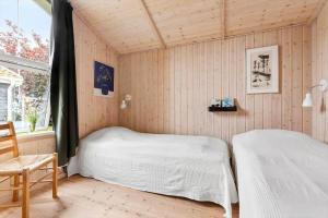 a bedroom with two beds and a chair and a window at 1497-N-Gilleleje-Parcelvej-3 in Gilleleje
