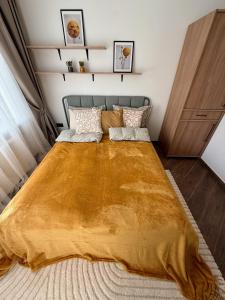 a bedroom with a bed with a yellow blanket on it at Cozy Stay Marijampolė in Marijampolė
