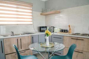a kitchen with a glass table with a vase of flowers at Unit 4 at Homely Escapes in Phalaborwa +6 photos