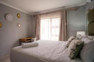 a bedroom with a large white bed with a window at Unit 4 at Homely Escapes in Phalaborwa
