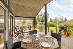 a patio with a table and chairs and a grill at 1566-Dronningmolle-Vipstjertvej-12 in Dronningmølle