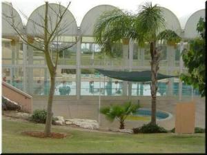 two palm trees in front of a large building at The Beach Garden Apt. in Caesarea