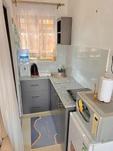 a small kitchen with a sink and a microwave at Luxury Homely Apt studio with pool in Kisumu