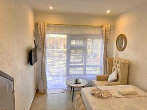 a bedroom with a bed and a table and a window at Luxury Homely Apt studio with pool in Kisumu