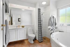 a white bathroom with a tub and a toilet and a sink at 1602-Vejby-Brondsholmvej-33 in Vejby +27 photos
