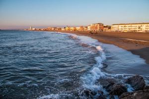 a beach with rocks and the ocean and buildings at Appartement en résidence Valras-Plage in Valras-Plage