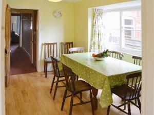 a dining room with a table with chairs and a bowl of fruit on it at The Castaway in Mundesley