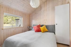 a bedroom with a white bed with red and yellow pillows at 1643-Hundested-Vaeselvaenget-3 in Hundested