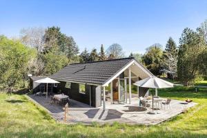 a small black cabin with a deck and umbrella at 1643-Hundested-Vaeselvaenget-3 in Hundested