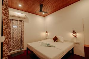 a bedroom with a bed and a ceiling fan at Marari Jackson Beach Homestay in Mararikulam
