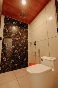 a bathroom with a toilet and a floral wallpaper at Marari Jackson Beach Homestay in Mararikulam